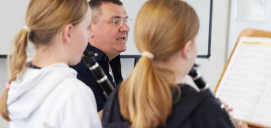 Zwei Mädchen spielen Klarinette angeleitet von ihrem Lehrer.
