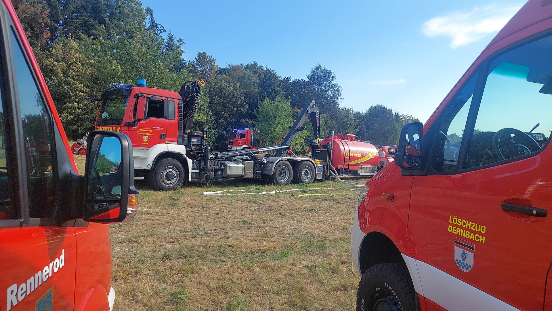 Durch zwei Feuerwehrfahrzeuge ist ein großer Löschtank zu sehen.