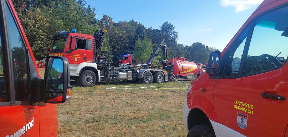 Durch zwei Feuerwehrfahrzeuge ist ein großer Löschtank zu sehen.