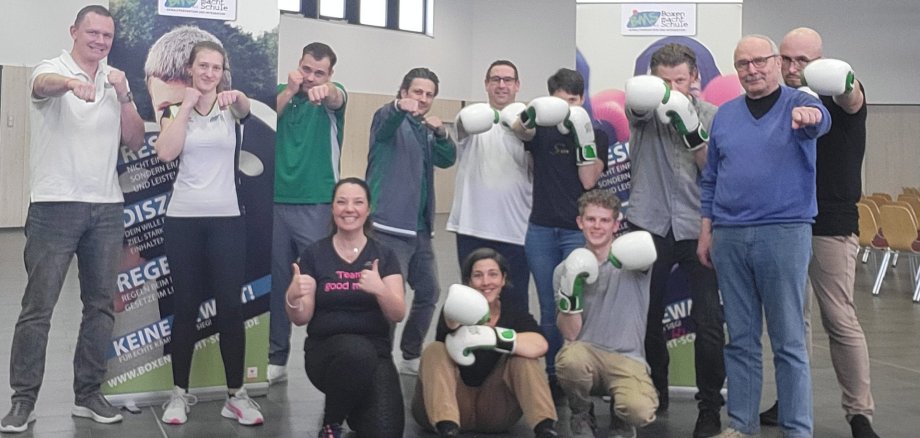 Frauen und Männer stehen in Boxhaltung, zum Teil mit Boxhandschuhen.