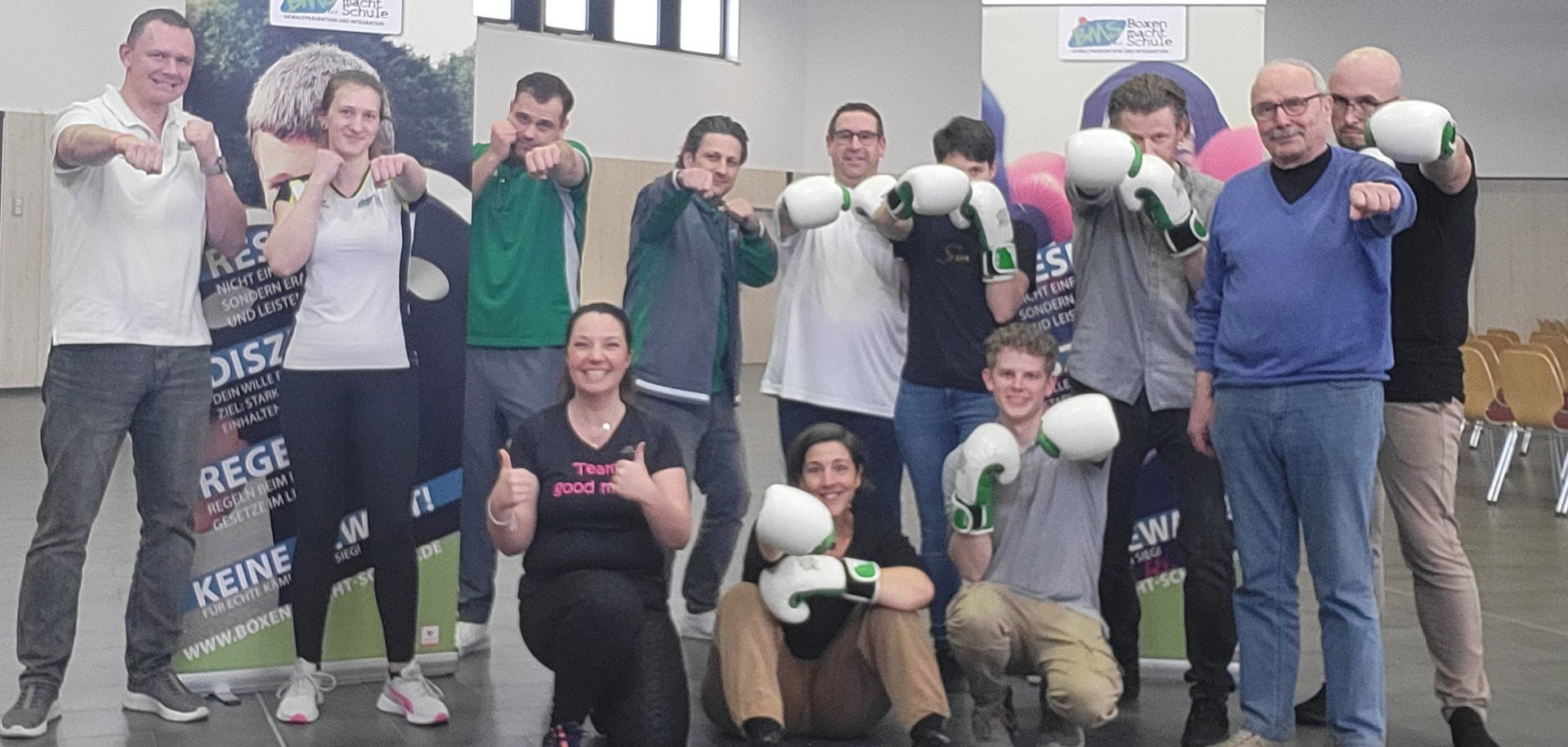 Frauen und Männer stehen in Boxhaltung, zum Teil mit Boxhandschuhen.