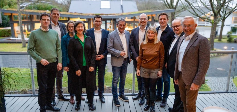 Mehrere Frauen und Männer stehen auf einer Holzterrasse.