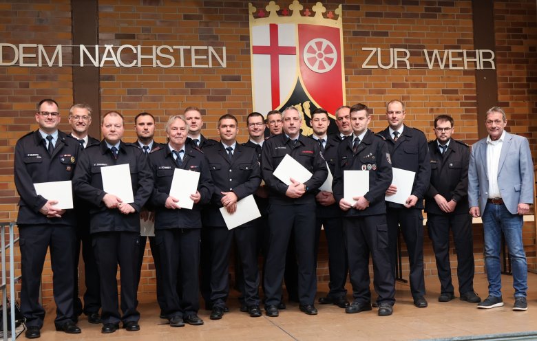 Auf einer Bühne stehen Feuerwehrleute in Dienstuniform.