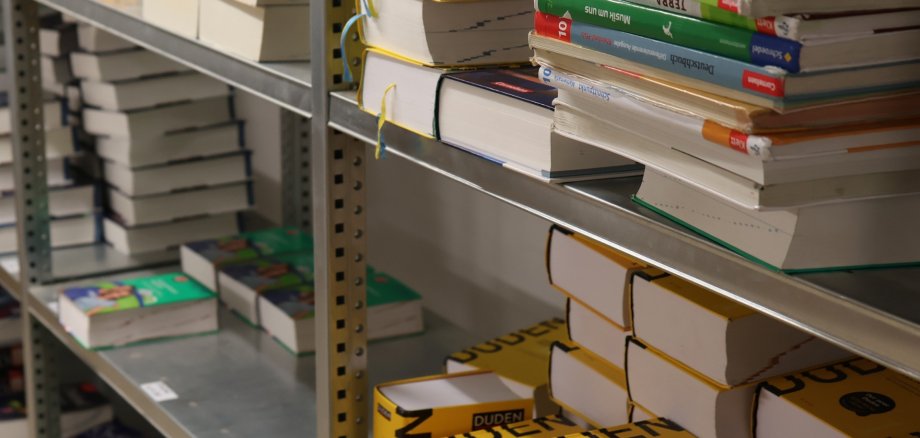 In einem Regal lagern verschiedene Schulbücher.