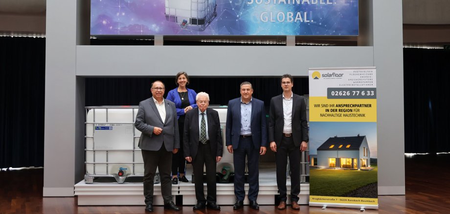 Eine Frau und vier Männer in Anzügen stehen neben einem Rollup mit der Aufschrift solarfloor.
