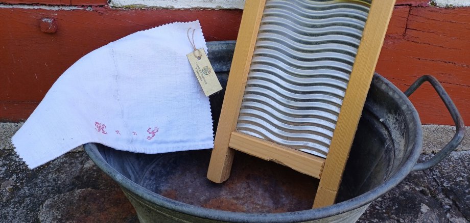 Ein Waschbrett steht in einer Zinnwanne.