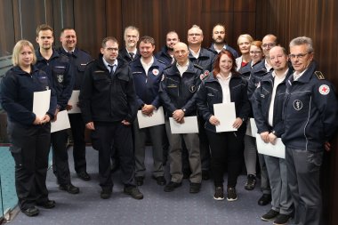 Eine Gruppe Menschen hält Urkunden in der Hand.