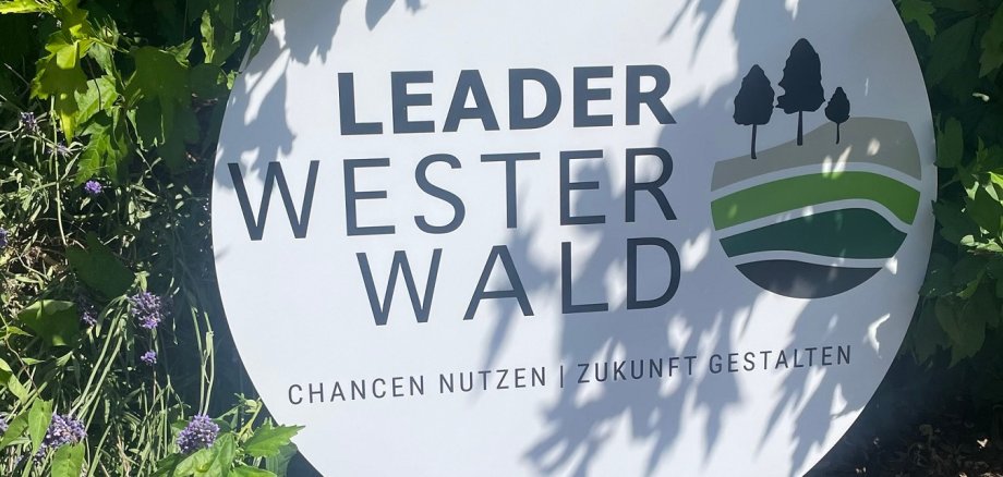 Im Grünen steht ein Schuld mit der Aufschrift Leader Westerwald,.