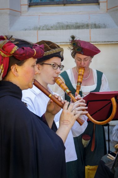 Frauen und Männer im mittelalterlichen Gewand spielen Blockflöten.