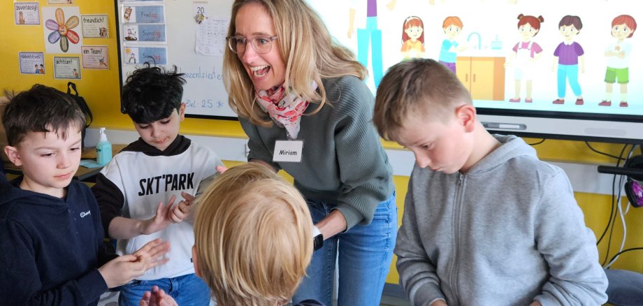 Angeleitet von einer Frau trainieren vier Jungen das richtige Händewaschen.