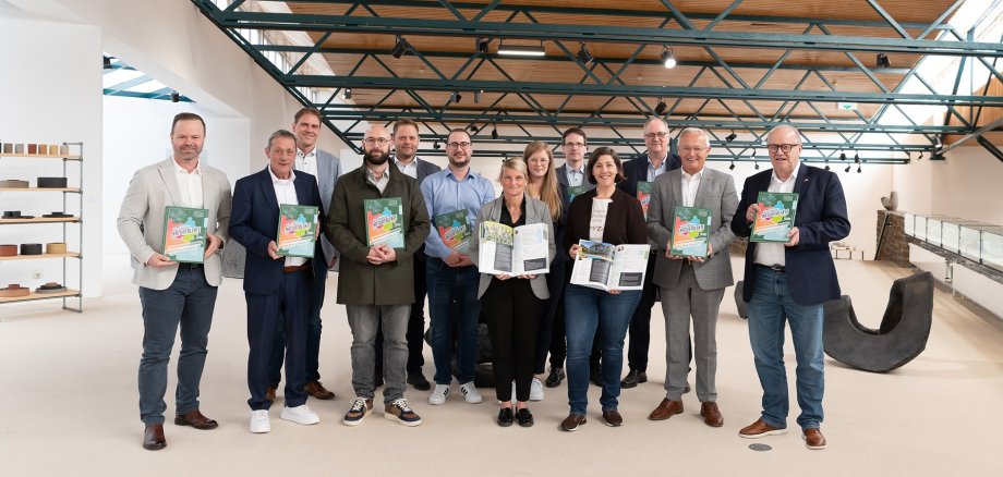 Männer und Frauen halten die Ausbildungsfibel in der Hand.