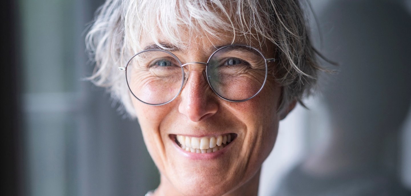 Foto des Kopfes einer Frau mit grauen Haaren und Brille.