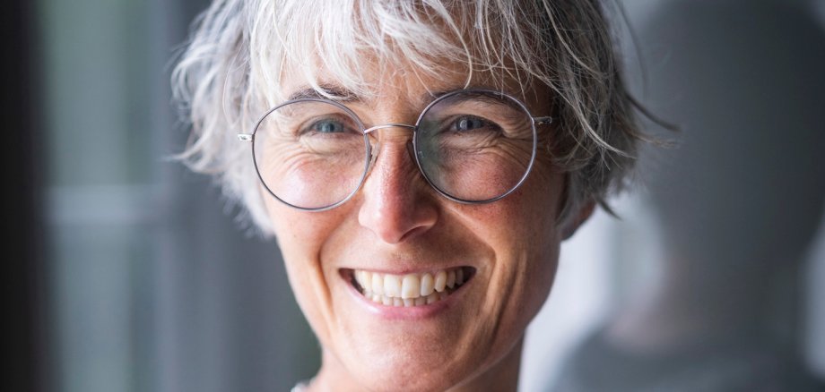 Foto des Kopfes einer Frau mit grauen Haaren und Brille.
