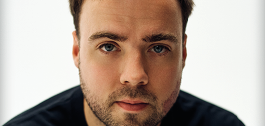 Ein junger Mann schaut in die Kamera.