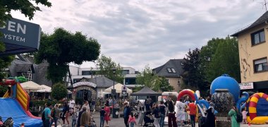 Auf einer Straße mit vielen Menschen stehen verschiedene aufblasbare Spielaktivitäten.