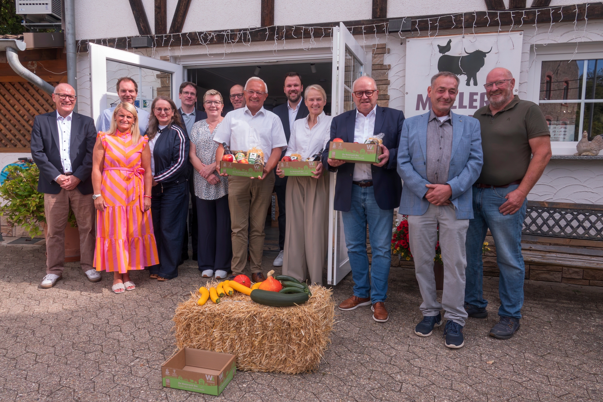 Vor einer Gruppe Menschen liegt ein Heuballen mit Kürbissen.
