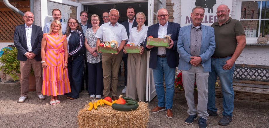 Vor einer Gruppe Menschen liegt ein Heuballen mit Kürbissen.