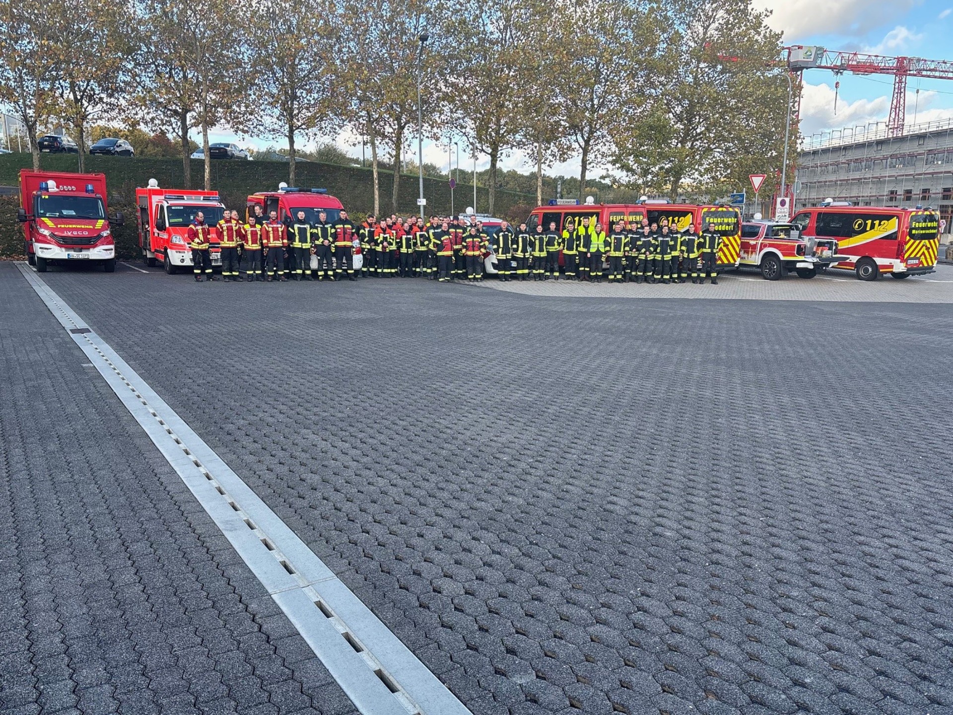 Auf einem Parkplätze stehen Feuerwehrfahrzeuge und Feuerwehrleute.