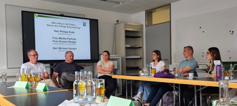 Mehrere Personen sitzen im Halbkreis vor einem Beamer.
