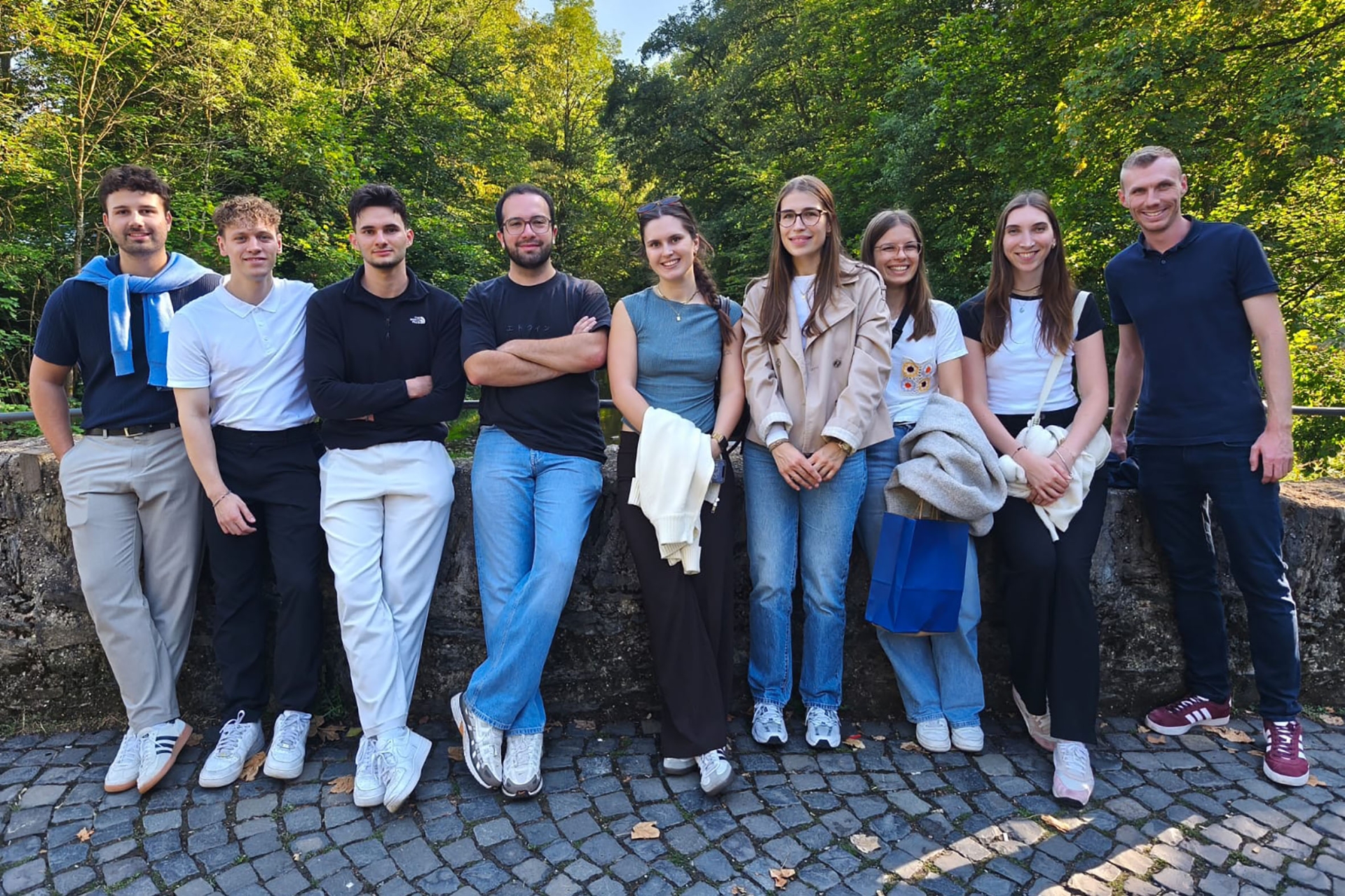 Eine Gruppe junger Menschen lehnt an einer Steinbrücke.