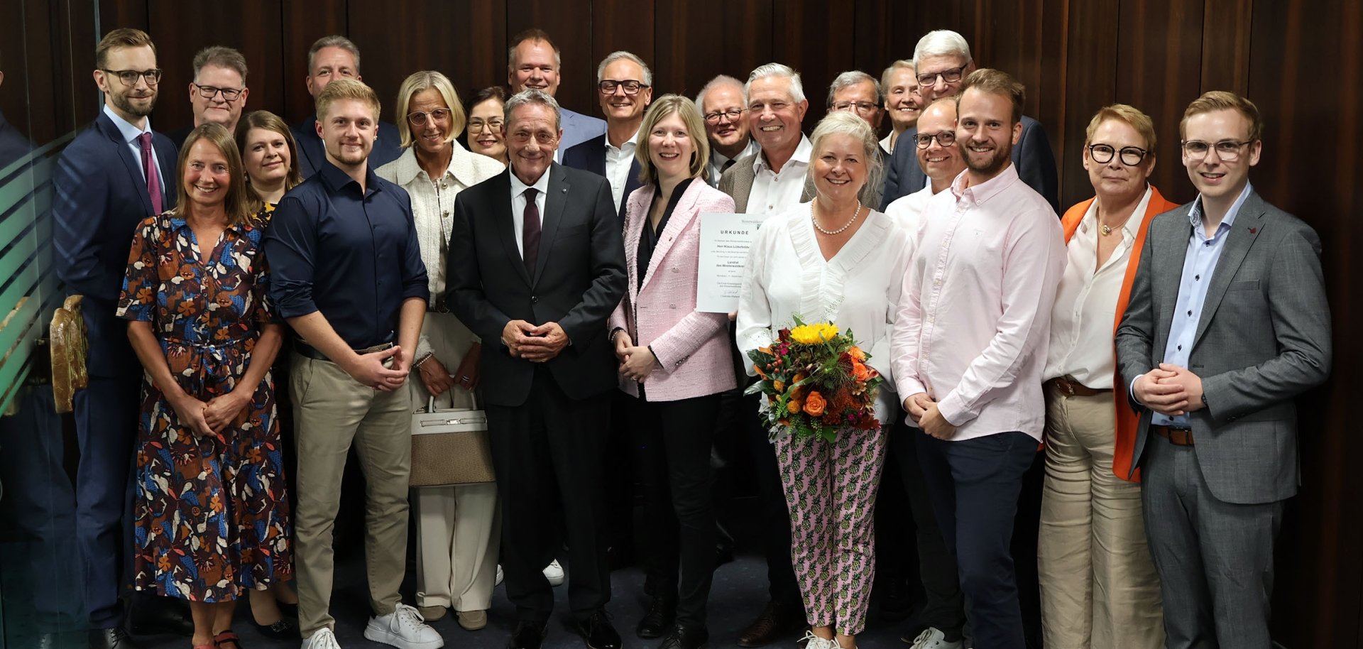 Eine große Gruppe Frauen und Männer steht in einem Flur.