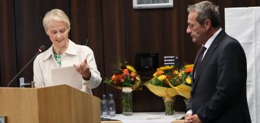 Eine Frau überreicht einem Mann eine Urkunde.