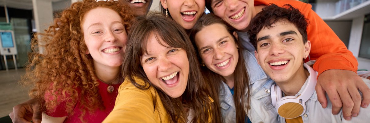 Eine Gruppe junger Leute unterschiedlicher Herkunft macht ein Selfie in einer Bibliothek.