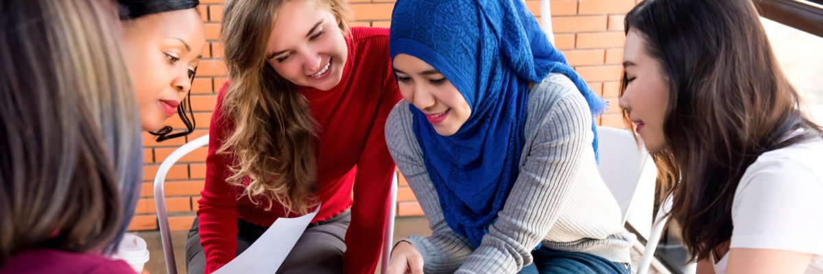 Drei zugewanderte Personen werden in einem Klassenzimmer unterrichtet.