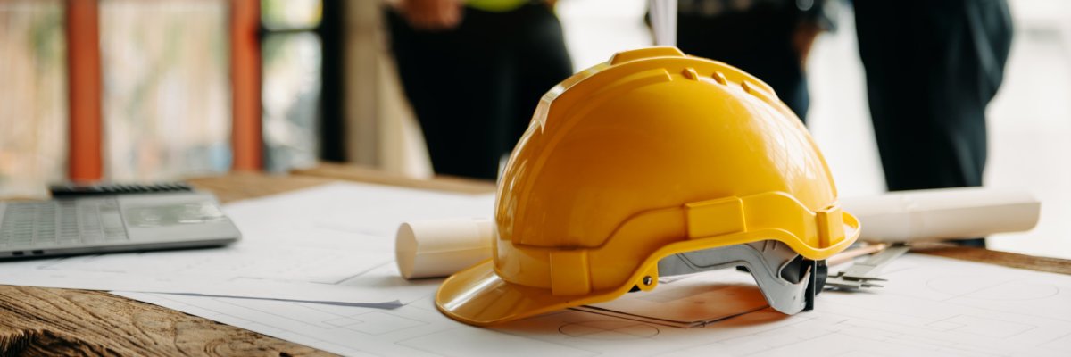 Ein Ingenieurteam mit Schutzhelmen trifft sich auf einer Baustelle zu einer Besprechung. 