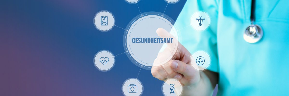 Ein Arzt sitzt mit einem Patienten an einem Schreibtisch und notiert etwas auf seinem Notizblock.