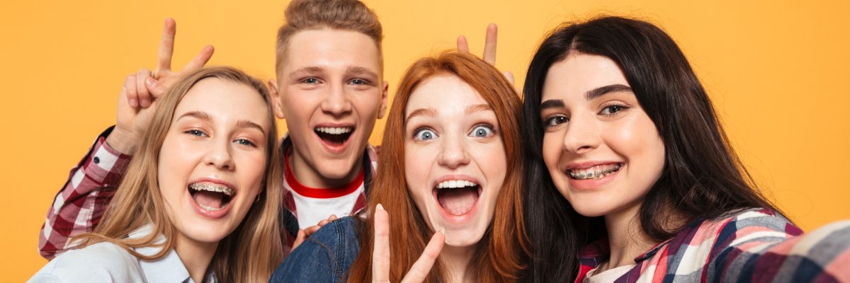 Eine Gruppe von Teenagern lacht in die Kamera vor einen bunten Hintergrund.