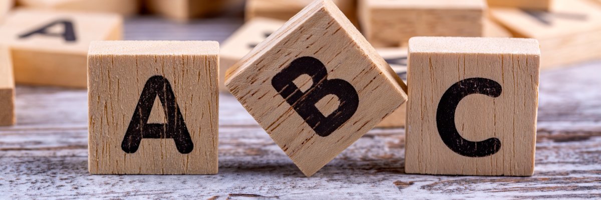 Drei Holzwürfel, die mit den Buchstaben "A", "B" und "C" beschriftet sind, sind nebeneinander aufgereiht.