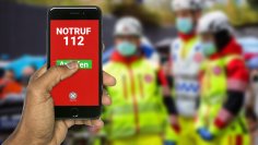 Eine Hand wählt über die 112 den Notruf.