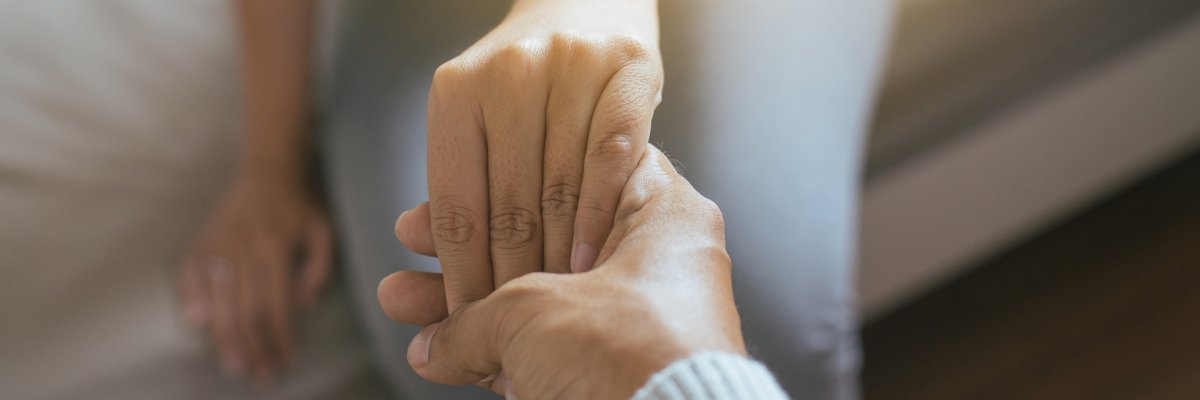 Mann gibt depressiver Frau die Hand.