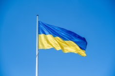 Die ukrainische Flagge weht im Wind vor einem blauen Himmel.