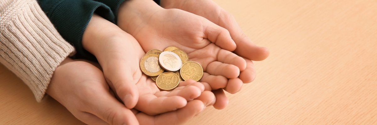 Hände eines Erwachsenen und eines Kindes halten Münzen.