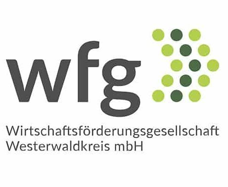 Im Logo ist der Schriftzug wfg - Wirtschaftsförderungsgesellschaft Westerwaldkreis mbH mit einem Pfeil zu sehen, der aus grünen Punkten besteht.
