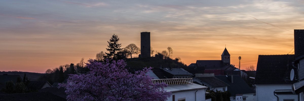auf einer Anhöhe eine Burg bei Sonnenuntergang.