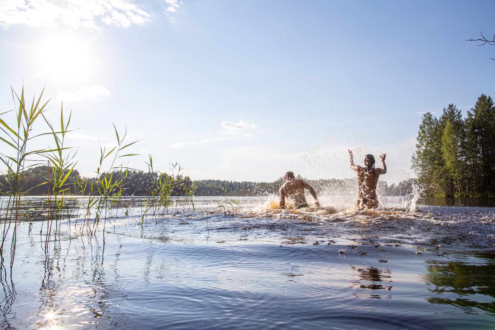 Ein Mann und eine Frau spritzen mit Wasser in einem Badesee an einem heißen Sommertag.