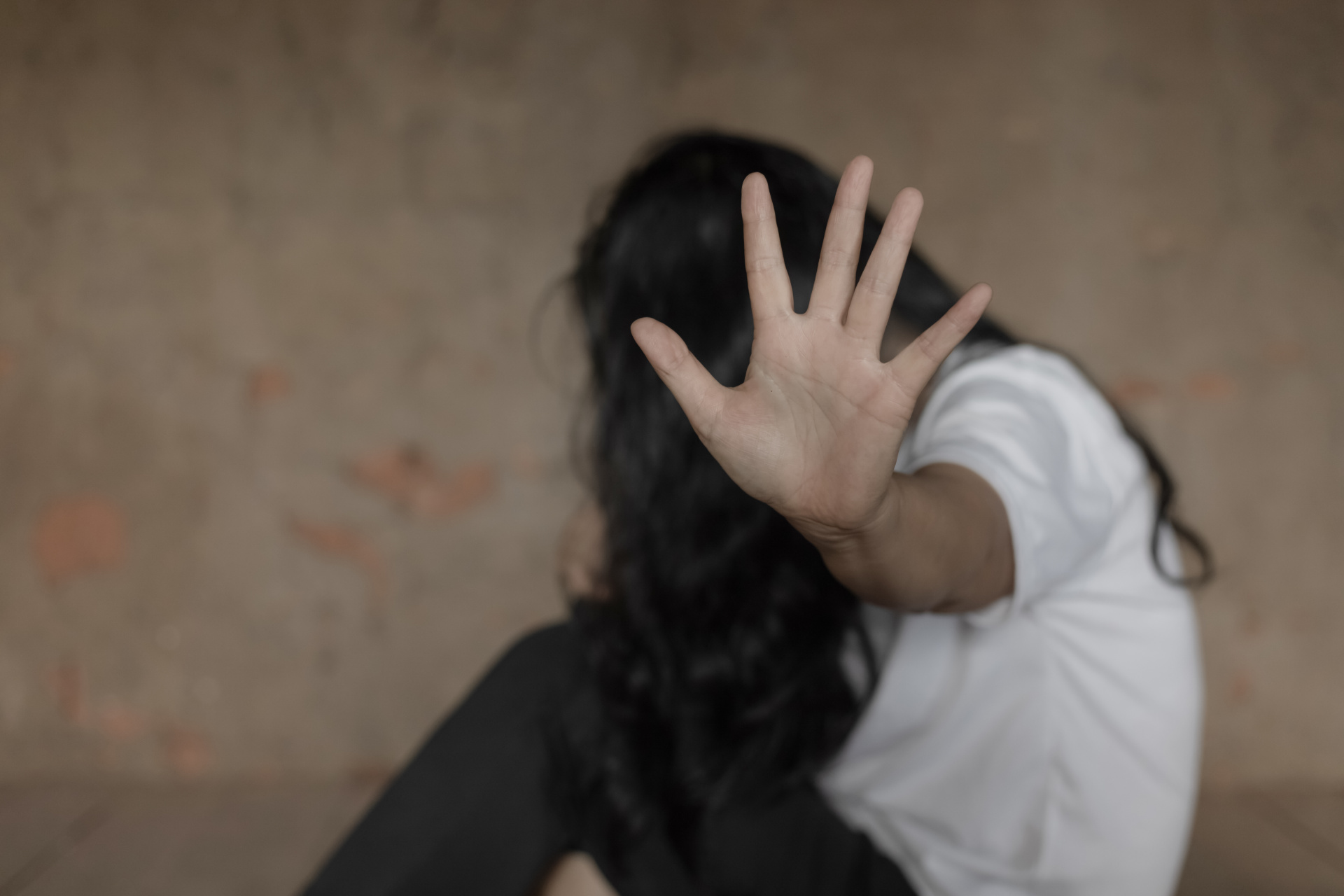 Eine Frau versteckt ihr Gesicht und hält eine Hand zur Abwehr Richtung Kamera.