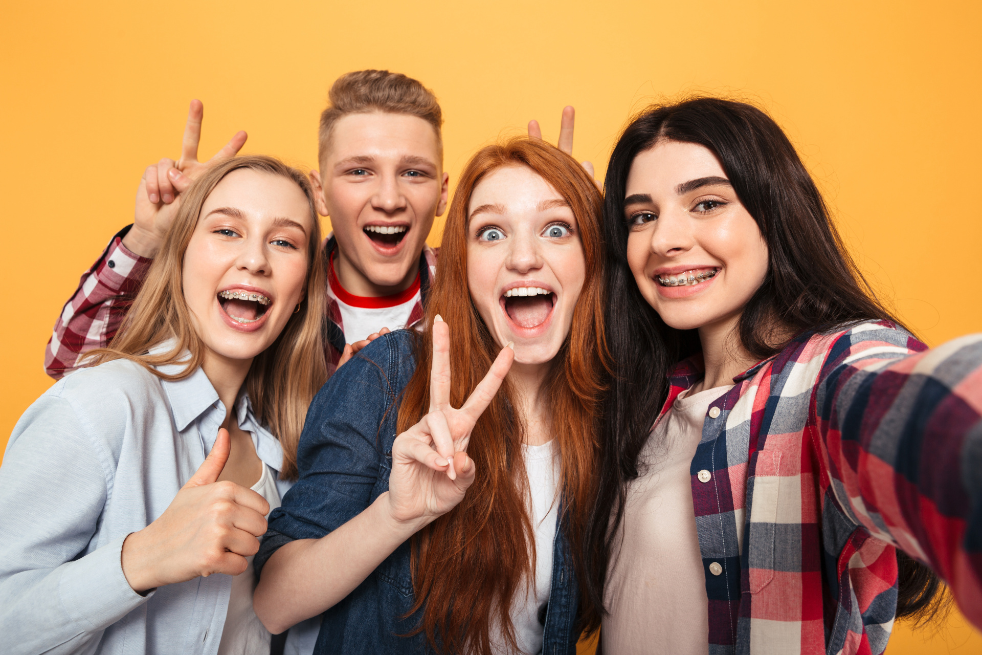 Eine Gruppe von Teenagern lacht in die Kamera vor einen bunten Hintergrund.
