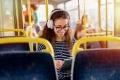 Eine junge Frau sitzt in einem Bus und liest.