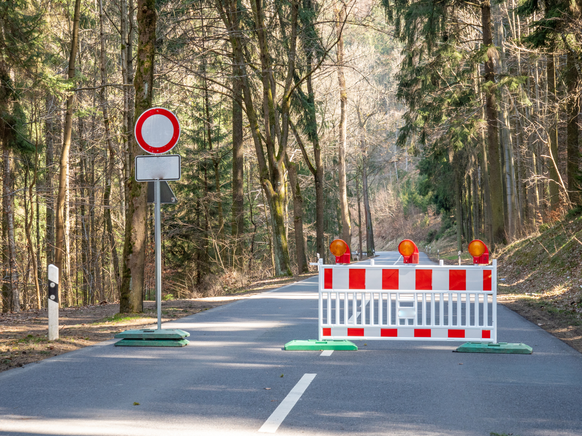 Eine Straße ist mit einer Warnbarke und einem Durchfahrtsverbotenschild gesperrt.