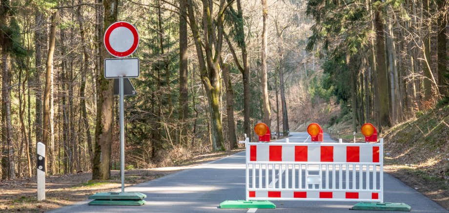 Eine Straße ist mit einer Warnbarke und einem Durchfahrtsverbotenschild gesperrt.