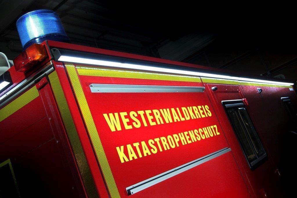Ein Feuerwehrfahrzeug mit der Aufschrift Westerwaldkreis Katastrophenschutz befindet sich in der Nacht im Einsatz.