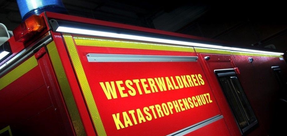 Ein Feuerwehrfahrzeug mit der Aufschrift Westerwaldkreis Katastrophenschutz befindet sich in der Nacht im Einsatz. 