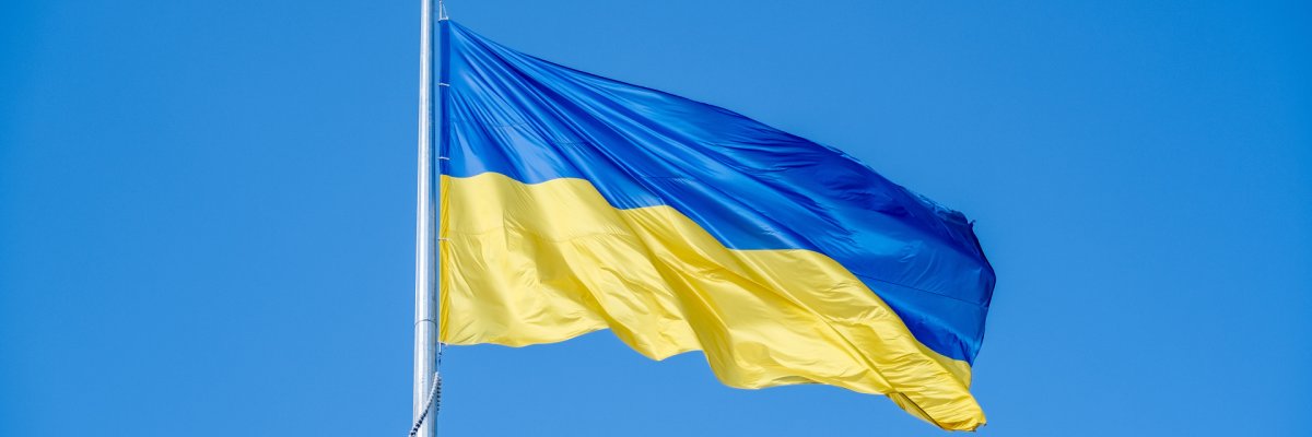 Die ukrainische Flagge weht im Wind vor einem blauen Himmel.
