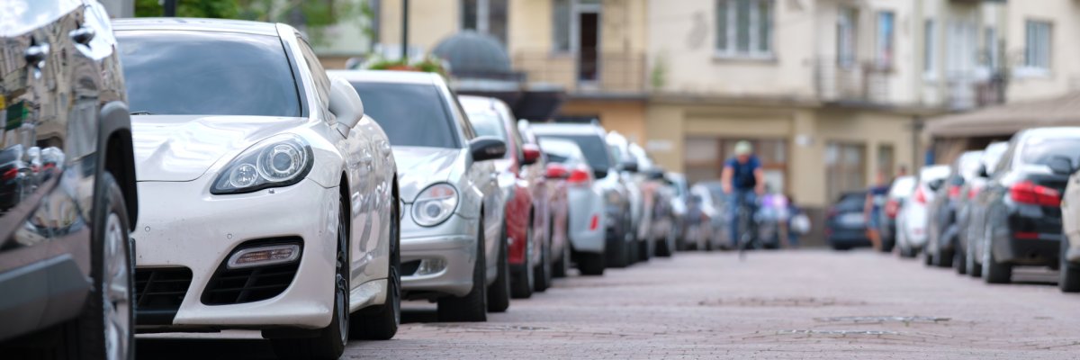 Eine Straße an der links und rechts jeweils parkende Autos stehen.