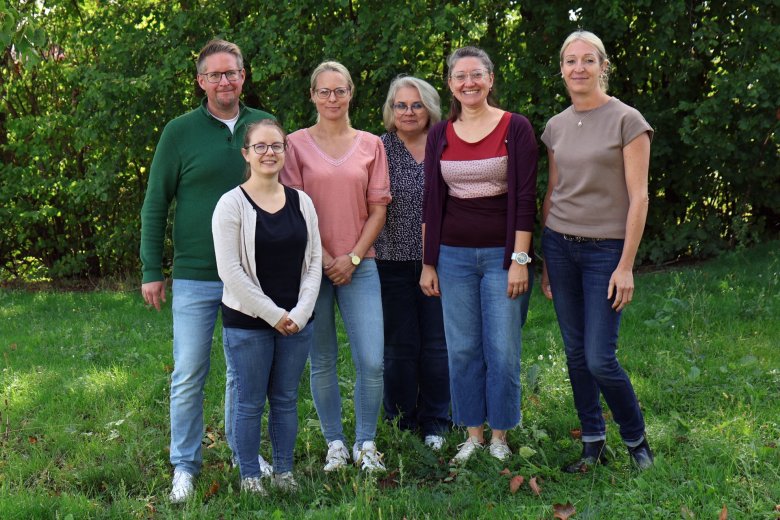 Eine Gruppe von Menschen steht im Grünen.