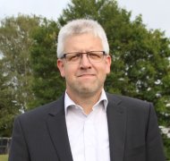 Kreisbeigeordneter Andreas Strüder steht auf einer Wiese und blickt in die Kamera.
